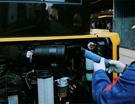 Technician replacing an air filter on Yuchai construction equipment.
