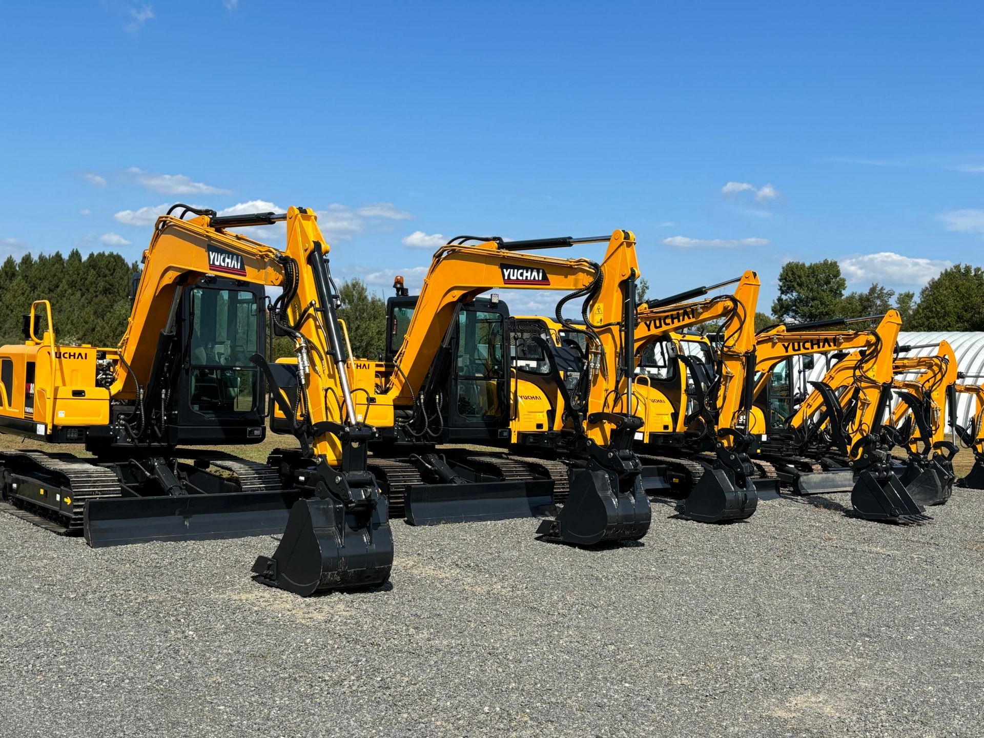 Several yellow Yuchai excavators parked outdoors.